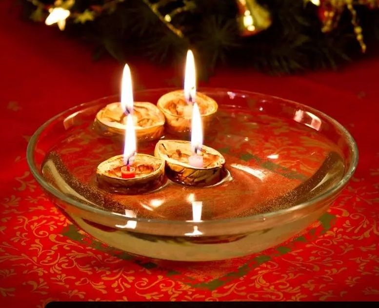 fotografia przedstawia 4 skorupki orzecha włoskiego, w środku których zamocowana został świeczka. Skorupki pływają po wodzie w szklanym naczyniu